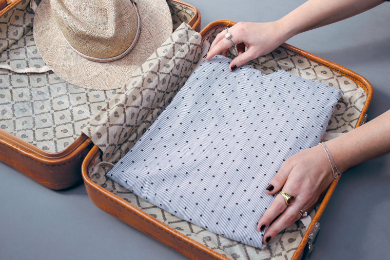 Place clothing into the suitcase Place clothing into the suitcase